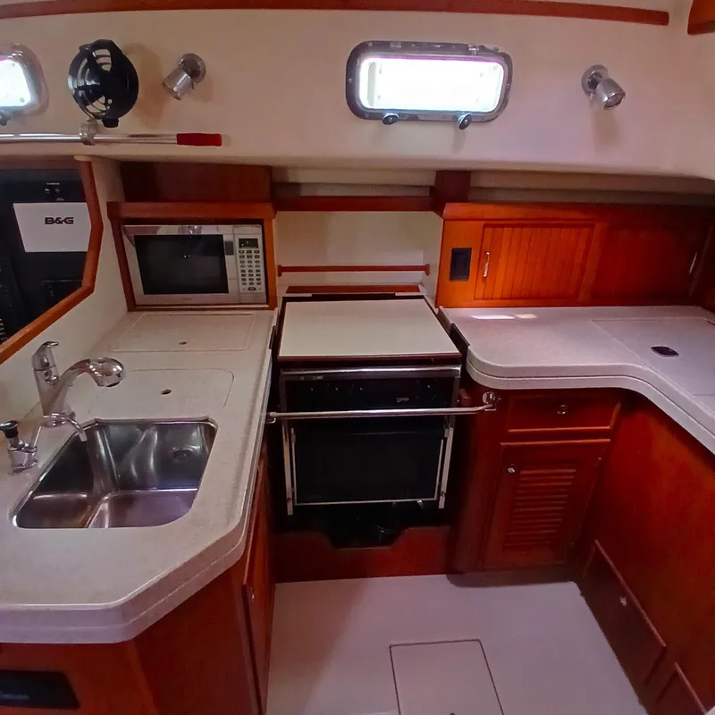 Slide: The Image of 2006 Island Packet 440 yacht kitchen with sink, stove, and microwave. - 26