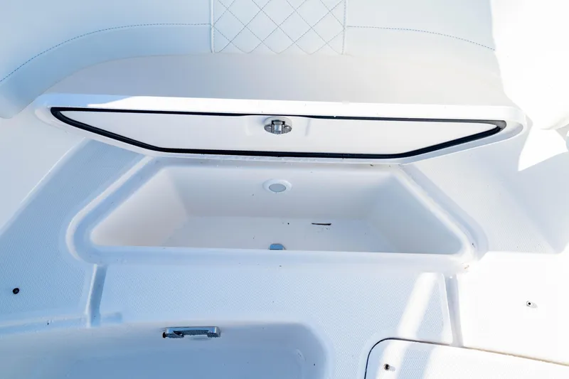 Slide: The Image of 2022 Edgewater 262 CX boat storage compartment, white interior, open lid. - 19