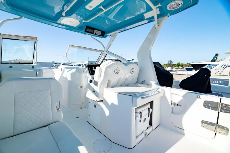 Slide: The Image of Interior of 2022 Edgewater 262 CX boat with white seating and blue canopy. - 28