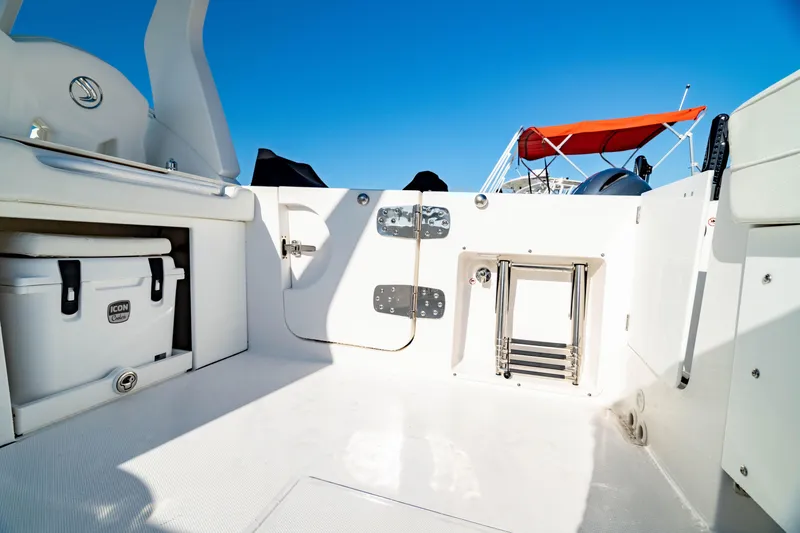Slide: The Image of 2022 Edgewater 262 CX boat interior with cooler and ladder, under clear blue sky. - 41