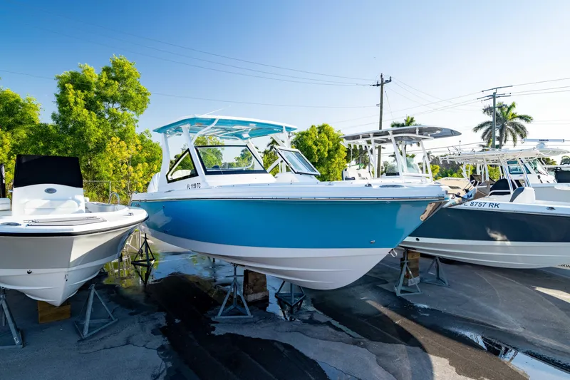 Slide: The Image of 2022 Edgewater 262 CX boat displayed outdoors on stands, surrounded by trees and other boats. - 43