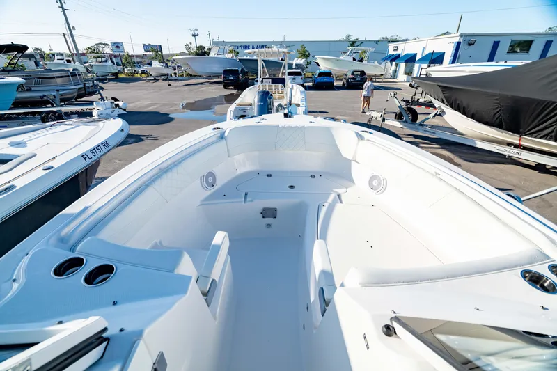 Slide: The Image of 2022 Edgewater 262 CX boat interior, spacious seating, parked in a marina with other boats. - 5