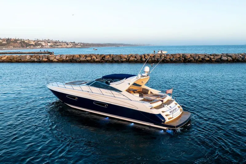 Slide: The Image of Luxurious 2004 Riva 59 Mercurius yacht cruising in serene blue waters near rocky shoreline. - 2