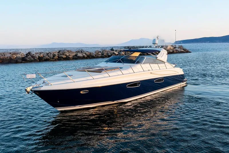 Slide: The Image of 2004 Riva 59 Mercurius yacht cruising on calm waters near rocky shoreline. - 6