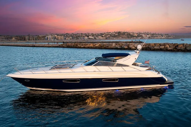 Slide: The Image of 2004 Riva 59 Mercurius yacht cruising at sunset near a rocky shoreline. - 7