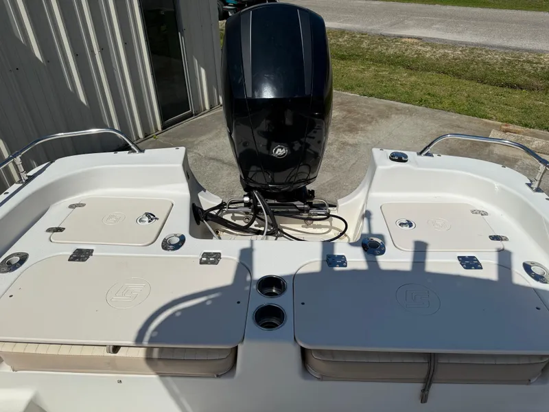 Slide: The Image of 2013 Carolina Skiff 218 DLV boat with outboard motor, docked near a building. - 7