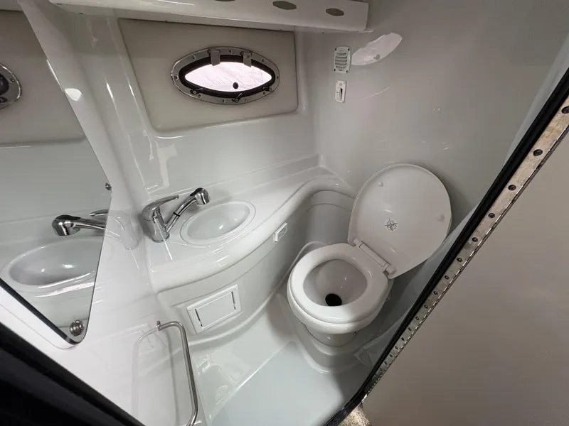 Slide: The Image of 2023 Crownline 264 CR boat bathroom with sink, toilet, and porthole window. - 10