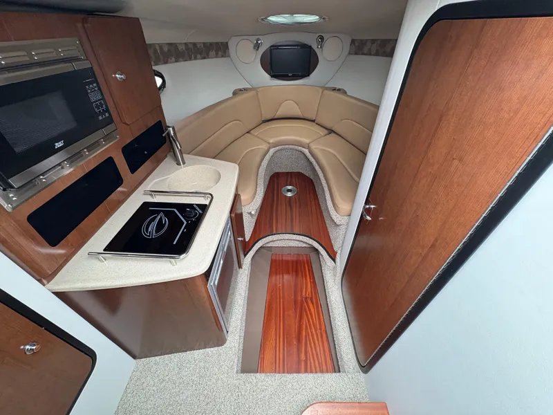 Slide: The Image of 2023 Crownline 264 CR cabin interior with kitchenette, seating, and wood accents. - 14