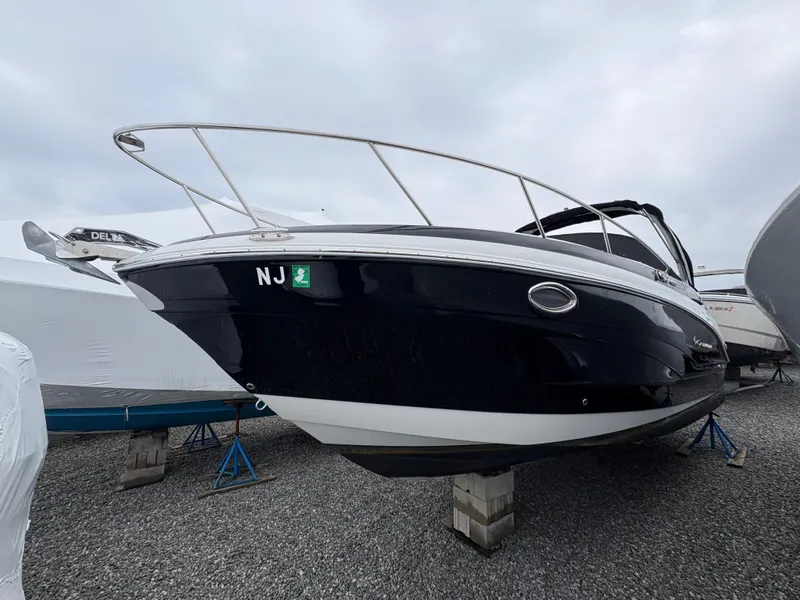 Slide: The Image of 2023 Crownline 264 CR boat on stands, black hull, overcast sky. - 4