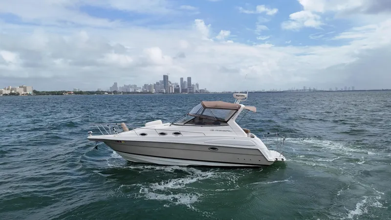 The Image of 2005 Regal Commodore 2860 boat cruising on open water with city skyline in background. - 0