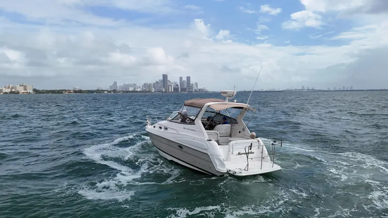 Slide: The Image of 2005 Regal Commodore 2860 boat cruising on open water with city skyline in background. - 11