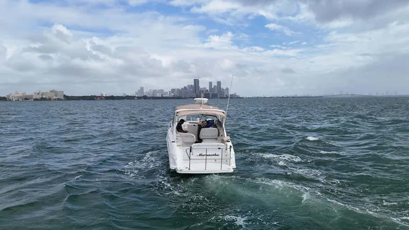 Slide: The Image of 2005 Regal Commodore 2860 boat cruising on open water with city skyline in background. - 12