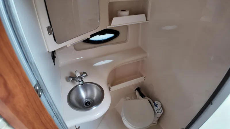 Slide: The Image of 2005 Regal Commodore 2860 boat bathroom with sink, toilet, and storage shelves. - 27