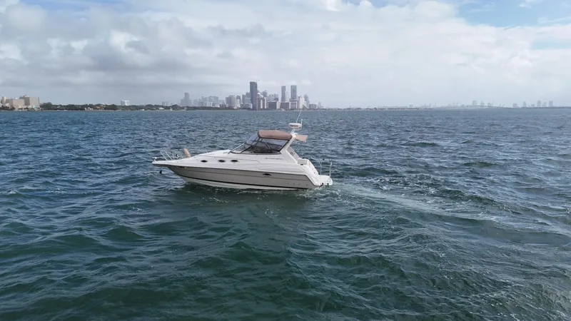 Slide: The Image of 2005 Regal Commodore 2860 yacht cruising on open water with city skyline backdrop. - 5