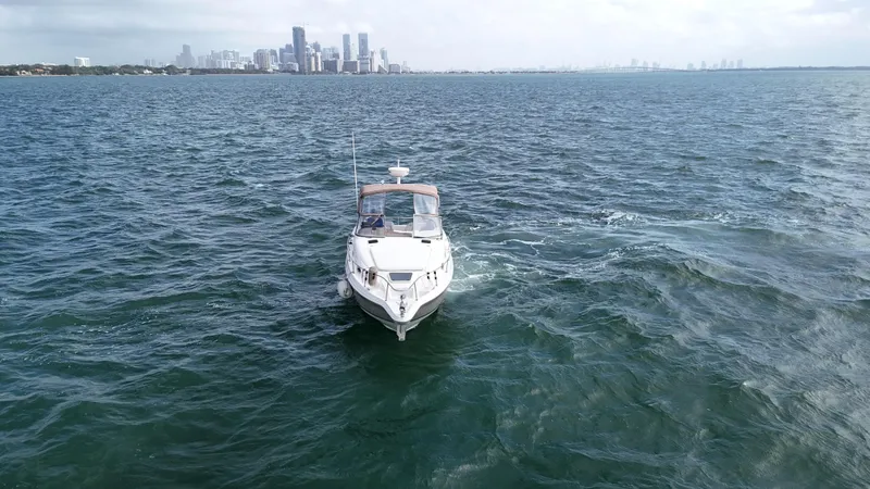 Slide: The Image of 2005 Regal Commodore 2860 boat cruising on open water with city skyline in background. - 7