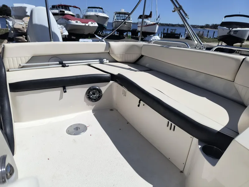 Slide: The Image of 2021 Stingray 192 SC boat interior with beige seating and cup holders, docked near other boats. - 10