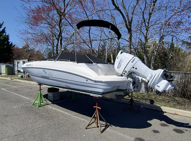 Slide: The Image of 2021 Stingray 192 SC boat on stands, parked outdoors with trees in the background. - 2