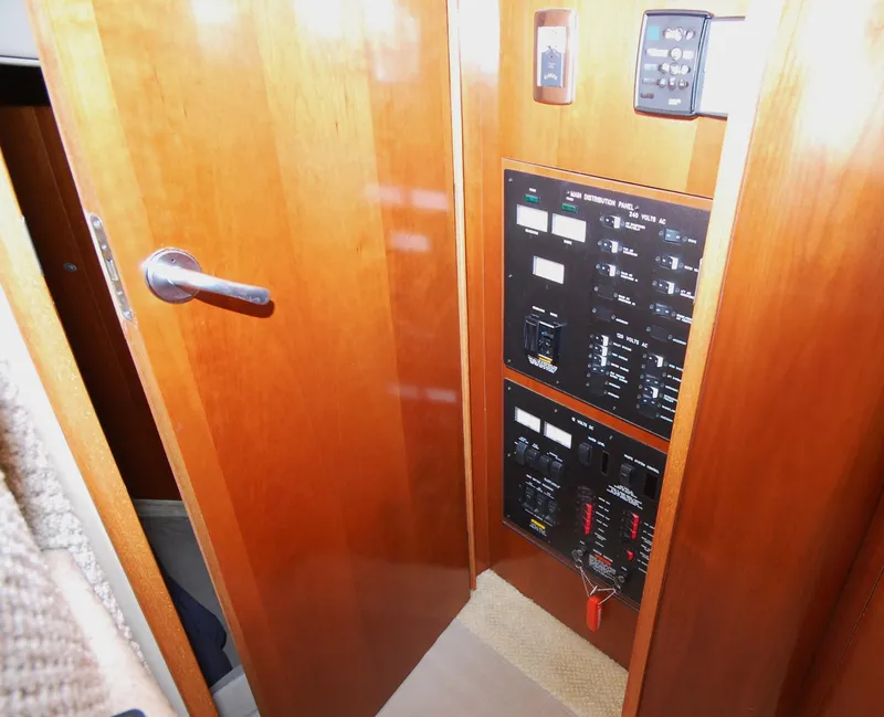 Slide: The Image of Electrical panel inside 2005 Sea Ray 390 Motor Yacht, featuring wooden cabinetry and control switches. - 41