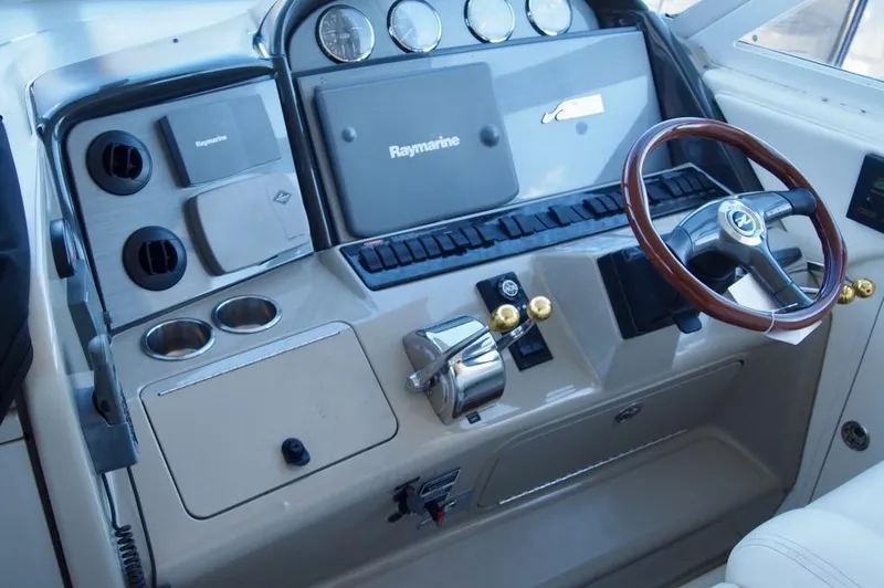 Slide: The Image of 2005 Sea Ray 390 Motor Yacht helm with Raymarine navigation and wood-accented steering wheel. - 6