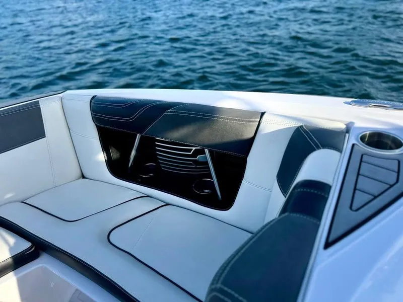 Slide: The Image of 2015 Nautique Super Air Nautique G21 boat interior with cushioned seating, cup holder, and water view. - 13