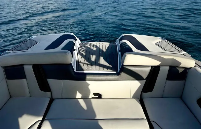 Slide: The Image of 2015 Nautique Super Air Nautique G21 boat interior with cushioned seating, overlooking calm water. - 5
