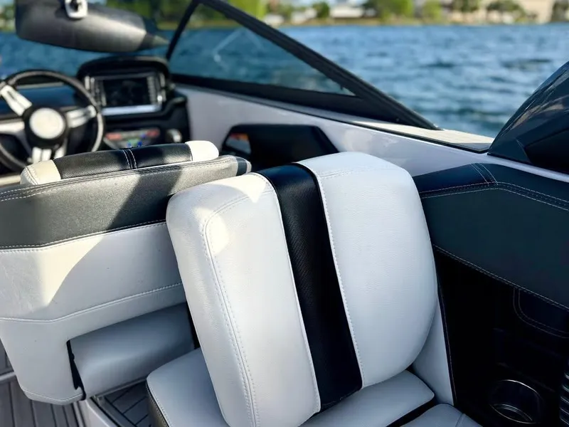 Slide: The Image of 2015 Nautique Super Air Nautique G21 interior with black and white seating by the water. - 9