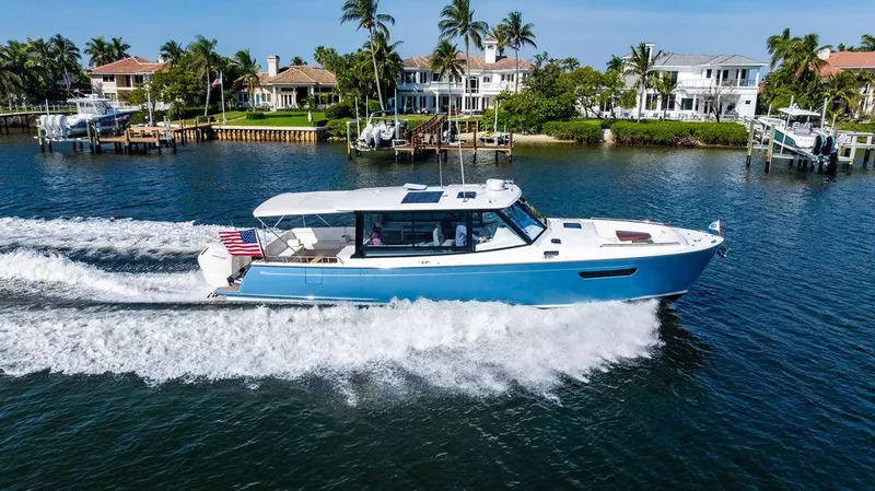 Slide: The Image of 2024 MJM 4 boat cruising on a sunny day near waterfront homes. - 14