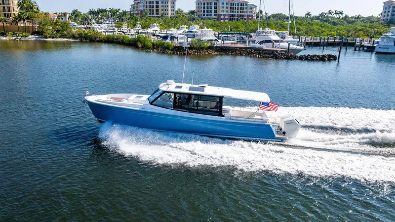 Slide: The Image of 2024 MJM 4 boat cruising on a serene waterway near a marina. - 15