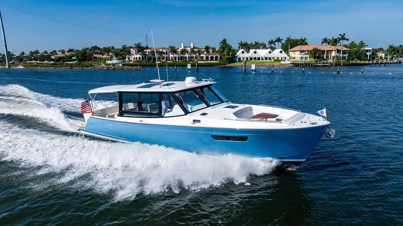 Slide: The Image of 2024 MJM 4 boat cruising on a sunny day near waterfront homes. - 5