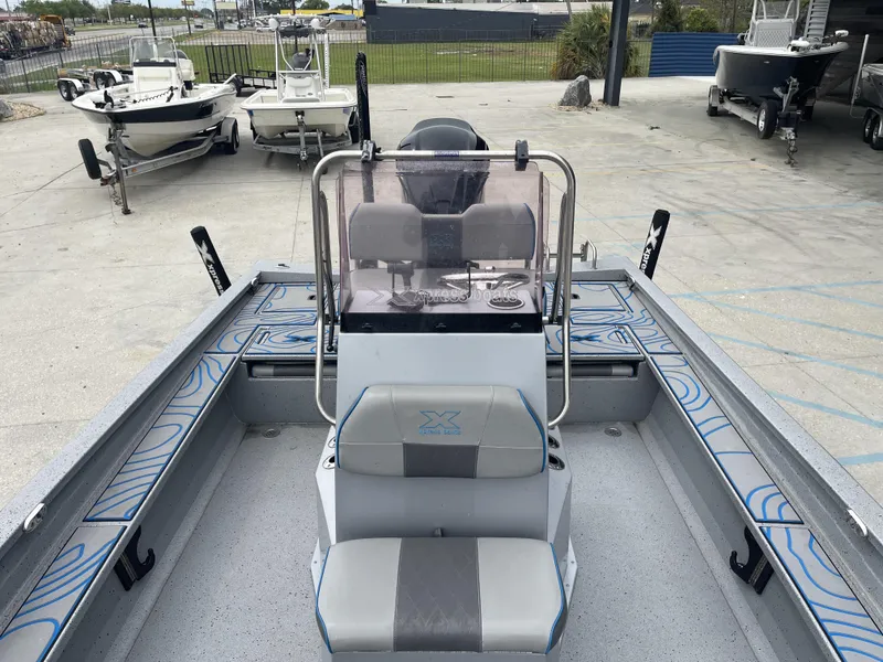 Slide: The Image of 2020 Xpress X23B boat interior with seating and control console in a showroom. - 11