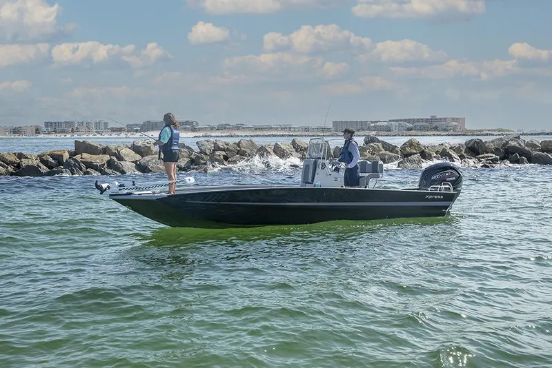 Slide: The Image of 2020 Xpress X23B boat navigating coastal waters with two people onboard. - 15