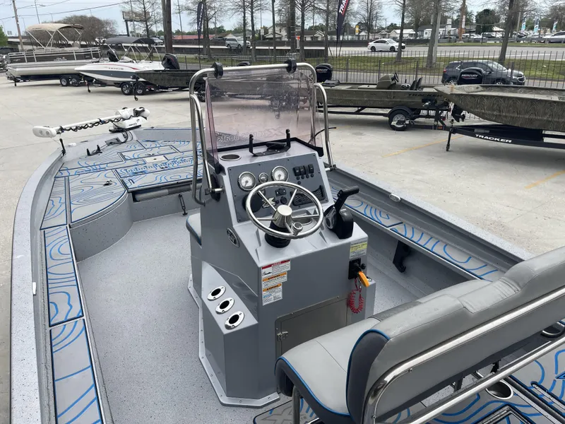 Slide: The Image of 2020 Xpress X23B boat interior with steering console and seating, parked in a lot. - 9