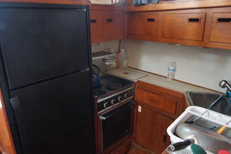 Slide: The Image of 1986 President 37 Sundeck yacht kitchen with stove, fridge, and wooden cabinets. - 5