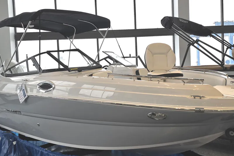 Slide: The Image of 2025 Stingray 211DC boat with sleek design and canopy, displayed indoors. - 0