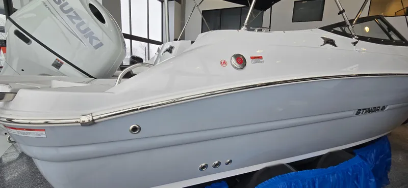 Slide: The Image of 2025 Stingray 211DC boat with Suzuki outboard motor in showroom. - 1