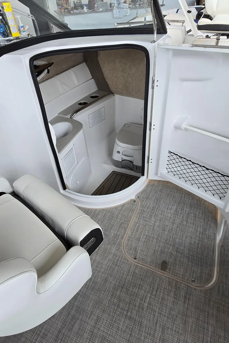 Slide: The Image of 2025 Stingray 211DC boat interior with seating and compact restroom. - 13