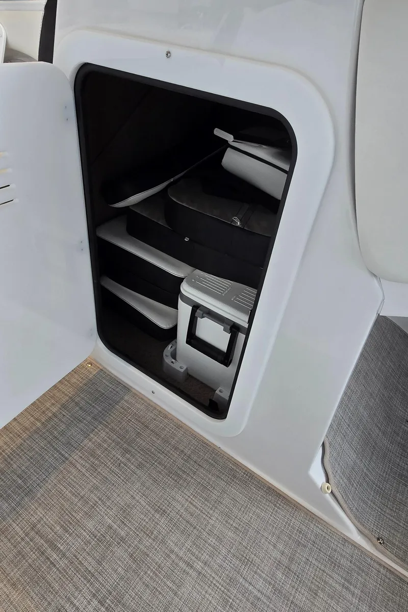 Slide: The Image of Storage compartment in a 2025 Stingray 211DC boat, featuring organized shelves and equipment. - 15