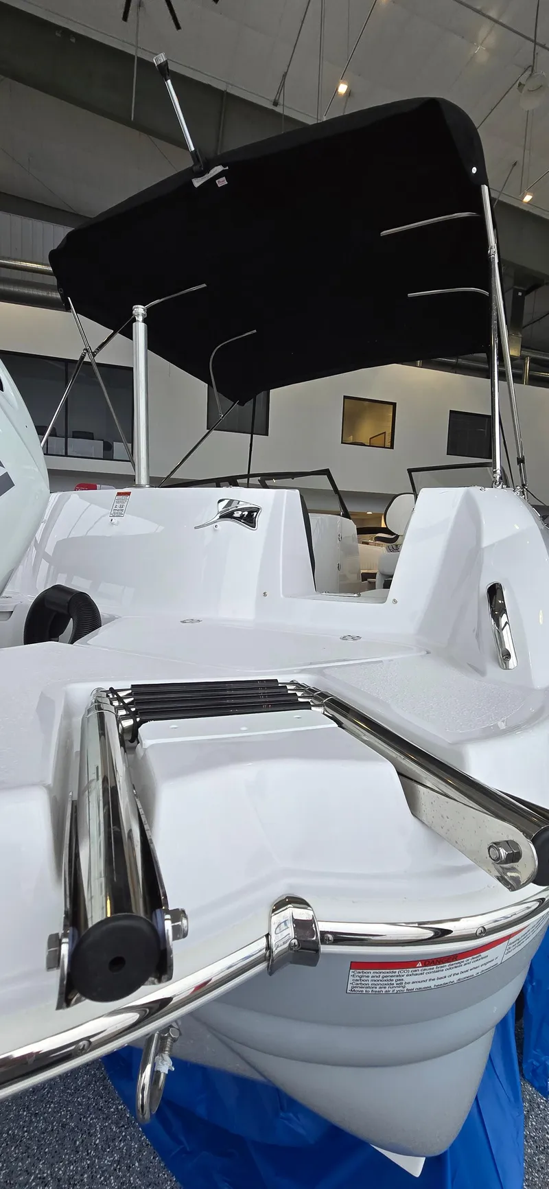 Slide: The Image of 2025 Stingray 211DC boat with sleek design and black canopy in showroom. - 16