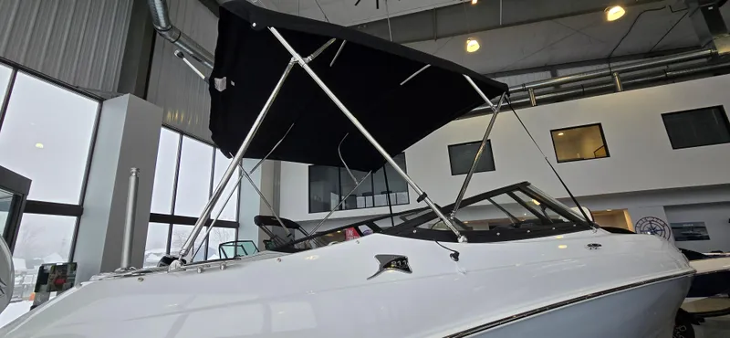 Slide: The Image of 2025 Stingray 211DC boat with canopy displayed indoors. - 22