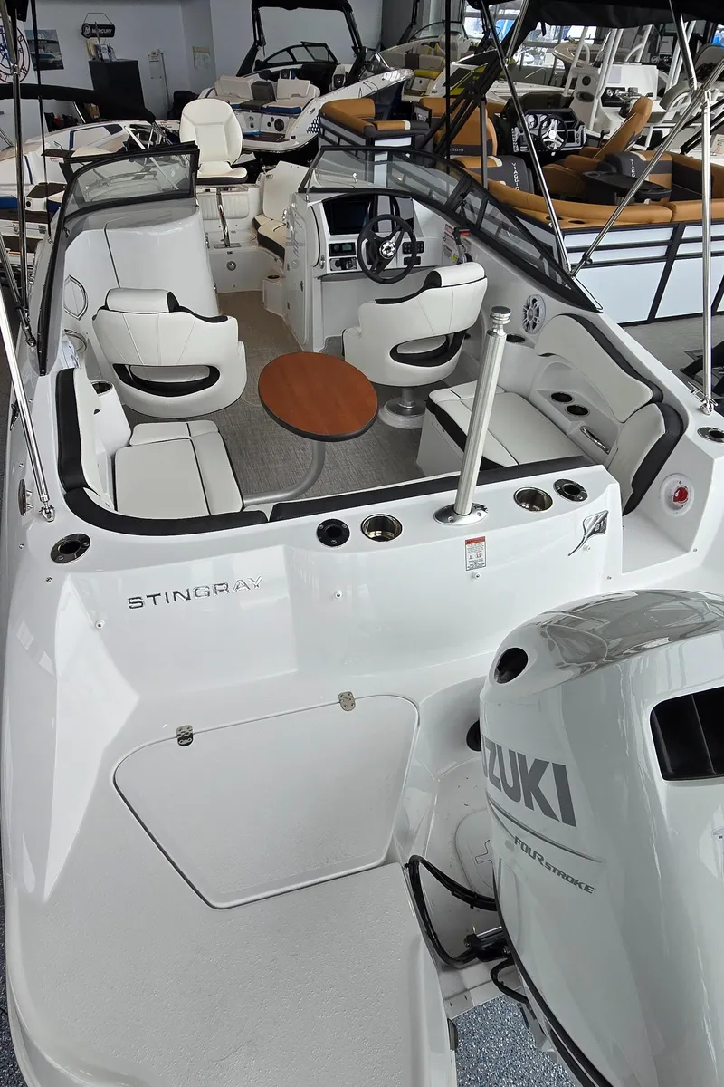 Slide: The Image of 2025 Stingray 211DC boat interior with Suzuki engine, featuring seating and a central table. - 5