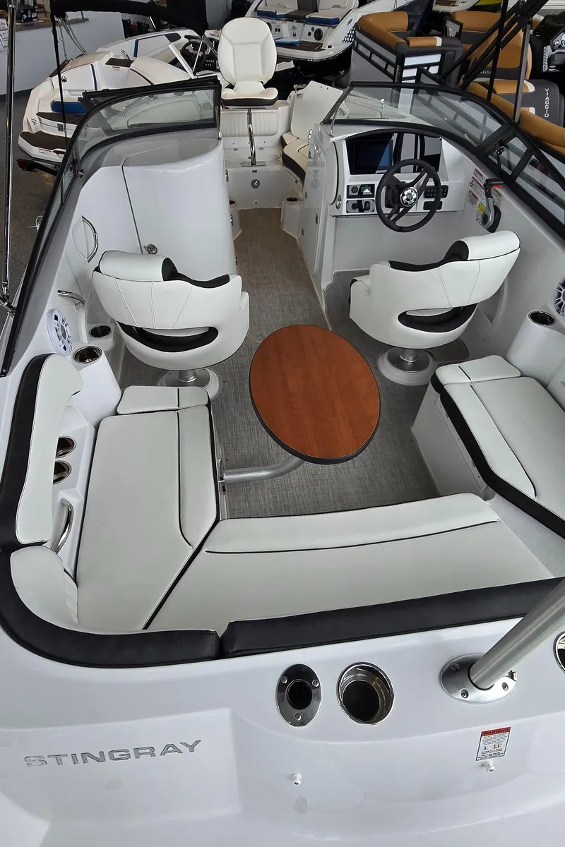Slide: The Image of 2025 Stingray 211DC boat interior with white seating and wooden table. - 7