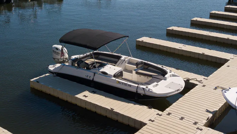 Slide: The Image of 2019 Stingray 212 SC boat docked on calm water with canopy. - 0