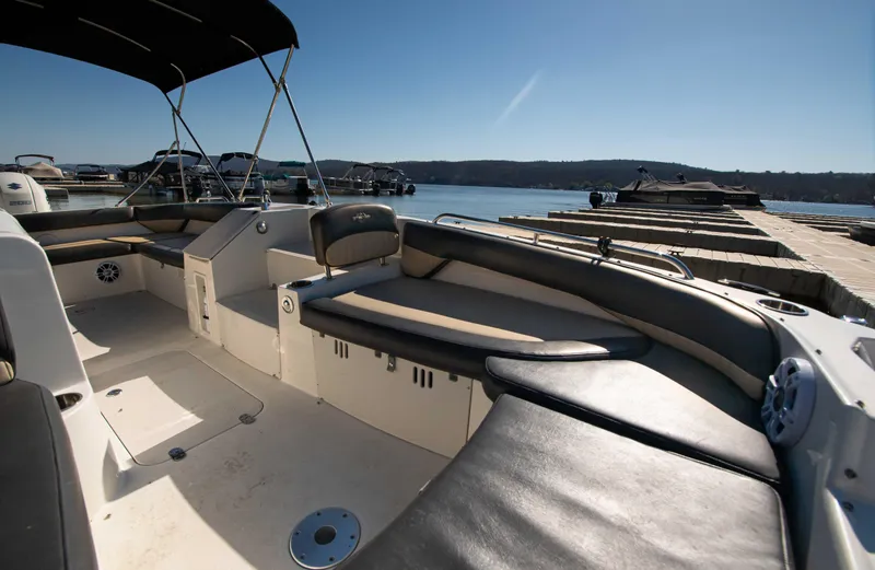 Slide: The Image of 2019 Stingray 212 SC boat interior with seating, docked by a serene lake. - 10