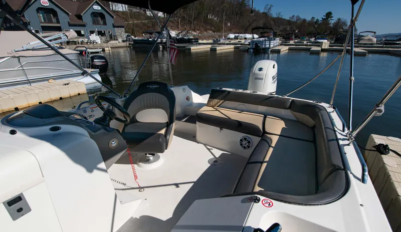 Slide: The Image of 2019 Stingray 212 SC boat interior at marina, featuring seating and steering console. - 13