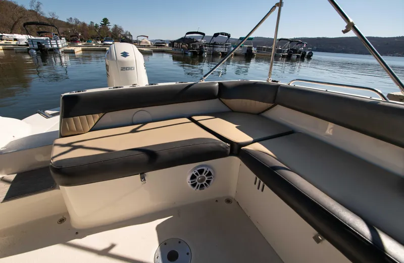 Slide: The Image of 2019 Stingray 212 SC boat with spacious seating, docked by a serene lake. - 15