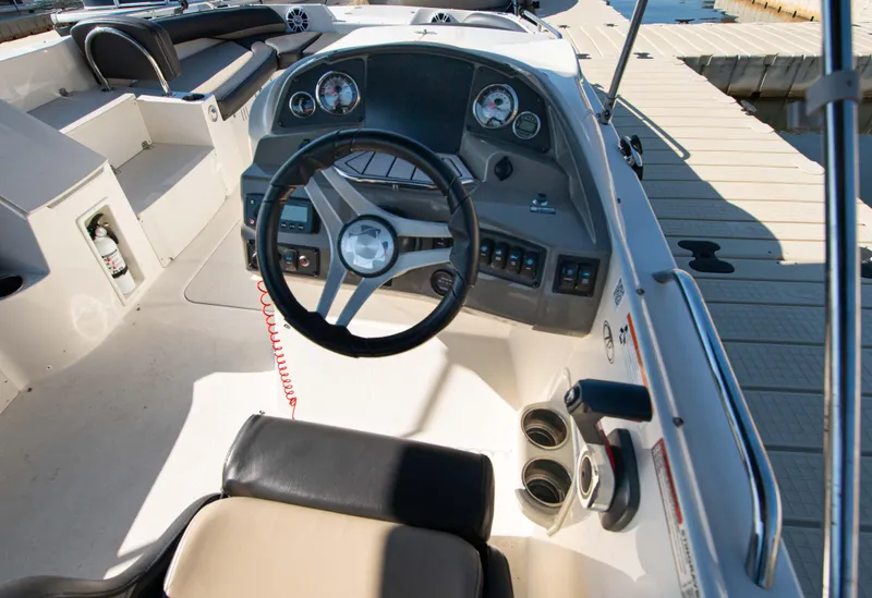 Slide: The Image of 2019 Stingray 212 SC boat cockpit with steering wheel and dashboard, docked at marina. - 17