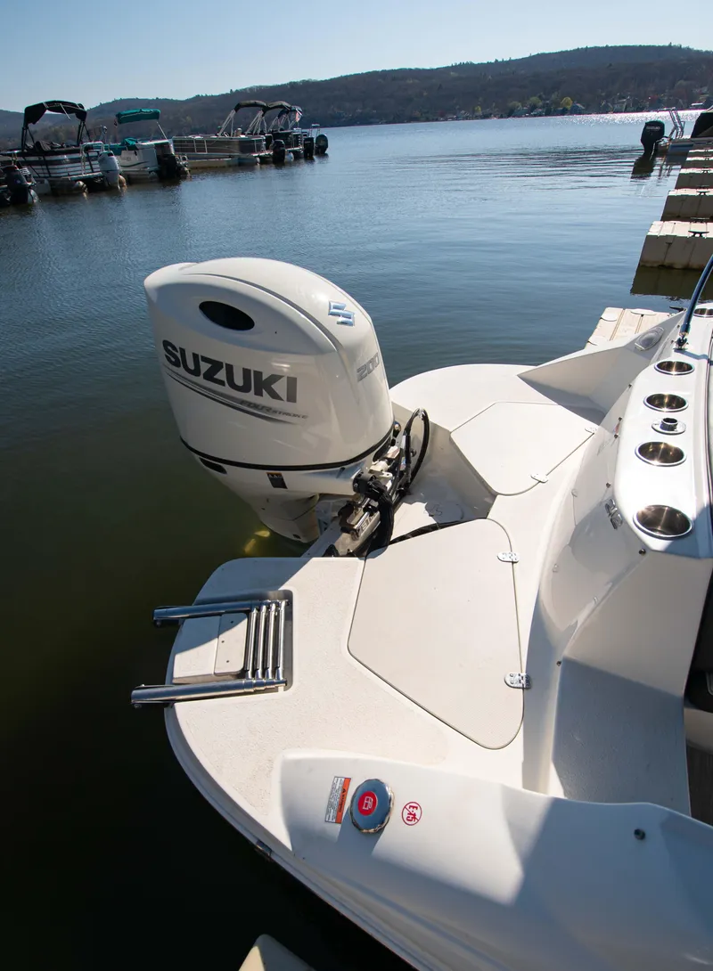 Slide: The Image of 2019 Stingray 212 SC boat with Suzuki outboard motor docked on a calm lake. - 20