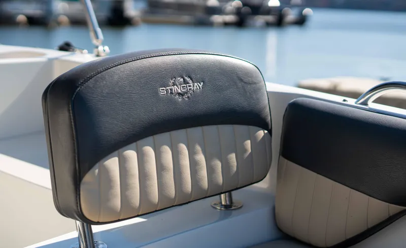 Slide: The Image of 2019 Stingray 212 SC boat seats with logo, docked by the water. - 21