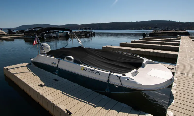 Slide: The Image of 2019 Stingray 212 SC boat docked at a marina, covered and ready for use. - 26