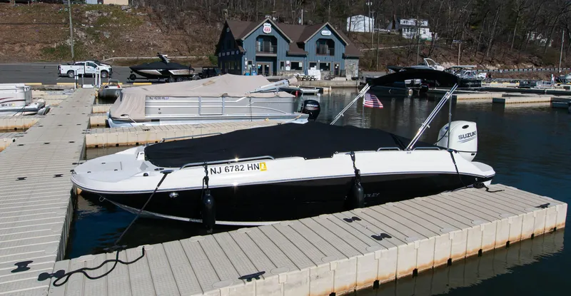 Slide: The Image of 2019 Stingray 212 SC boat docked at a marina with covered seating area. - 27